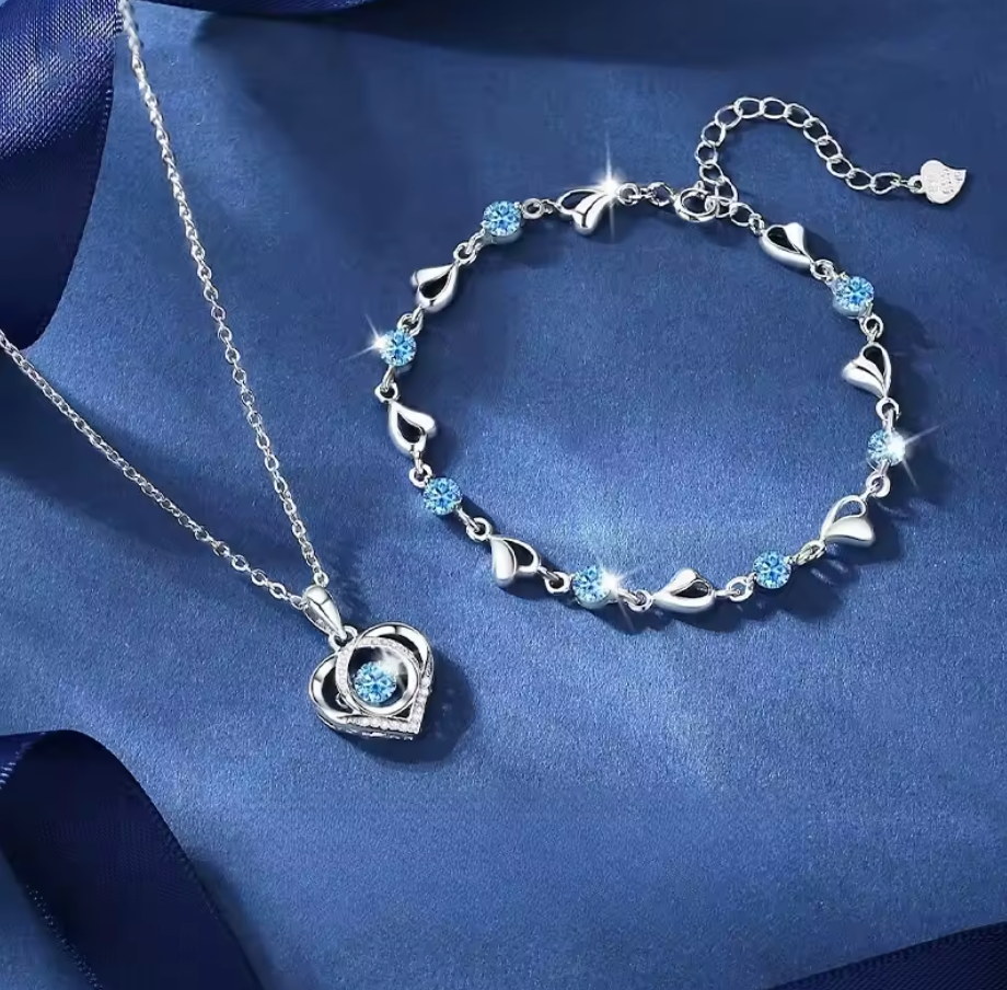 Silver heart necklace and bracelet on blue fabric
