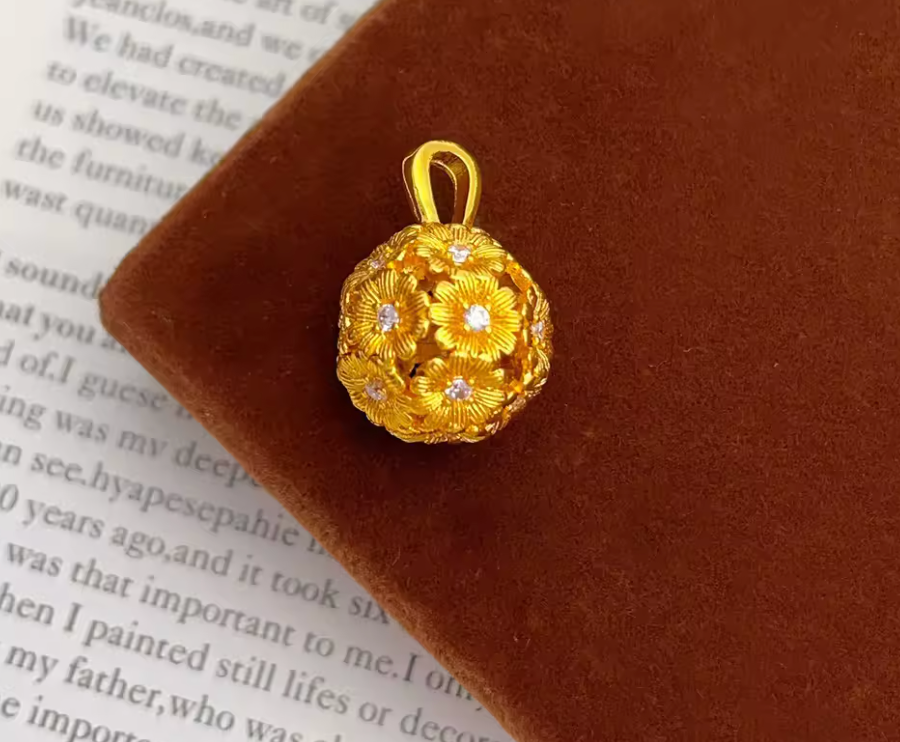 Gold-tone flower-patterned spherical pendant close-up